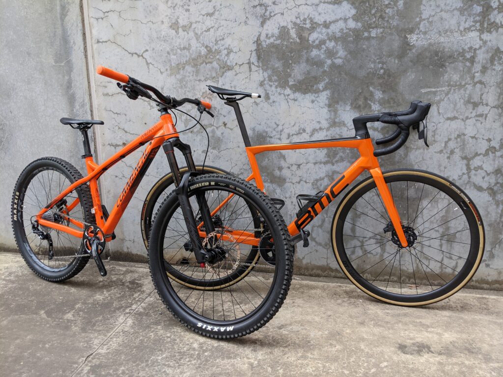 An orange Commencal & an orange BMC road bike leaning against the wall ready to be photographed for the bicycle photography page