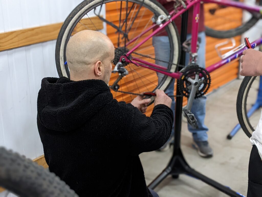 Checking chain length on a purple roadbike at 1226 Bikes bicycle maintenance course