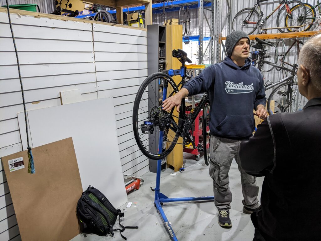Ben showing a cassette on a bicycle on a workstand at the 1226 bicycle maintenance course